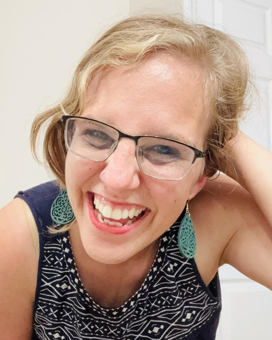 Chelsea Leathers, smiling, wearing glasses and teal earrings